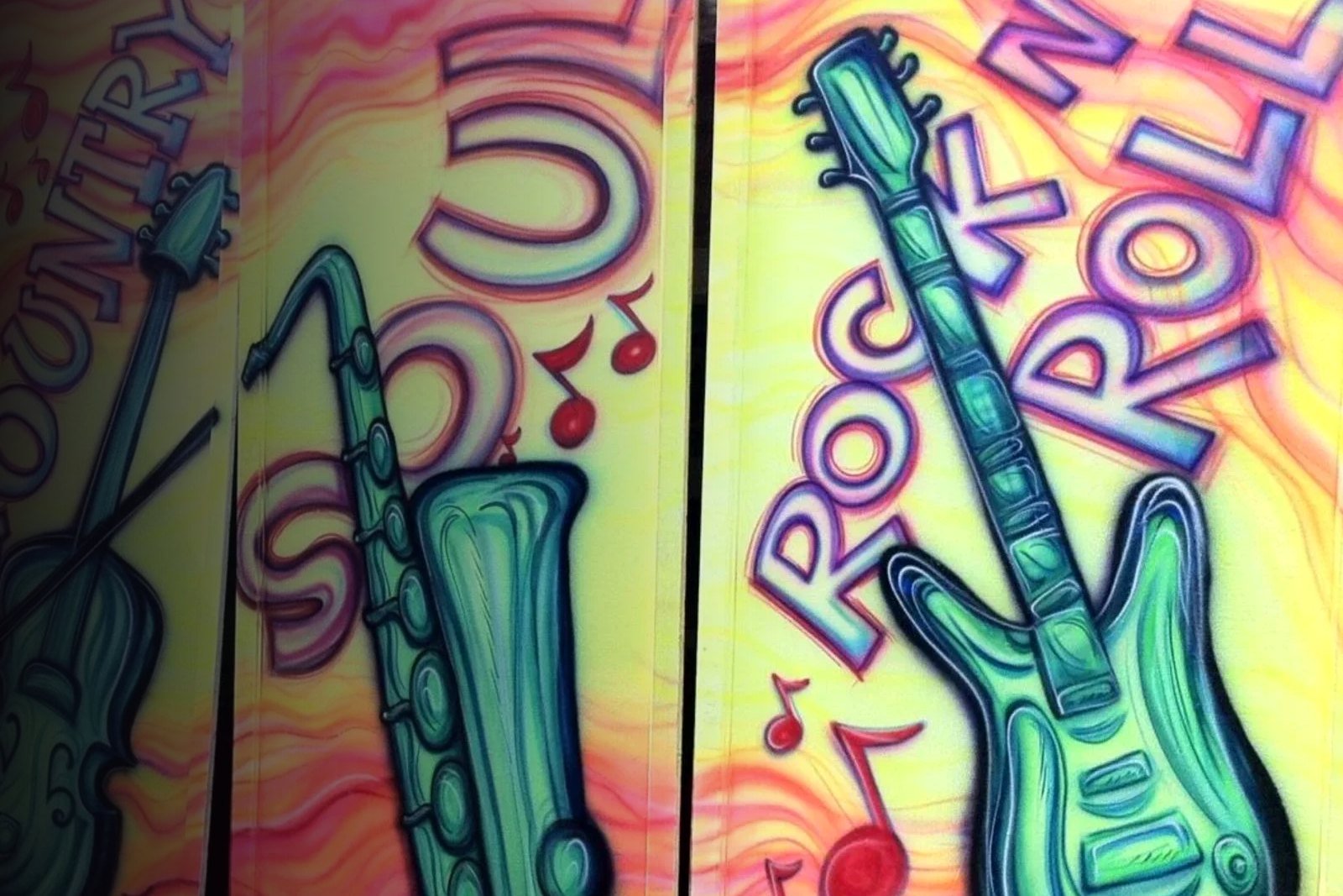Airbrushed panels of a violin, saxophone and electric guitar labeled Country, Soul and Rock n Roll